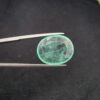 ​A rare 8.05-carat natural Pakistani Emerald gemstone resting flat on a white textured leather insert inside a display box. The loose, earth-mined beryl gem is precision cut into a well-proportioned oval shape, showcasing a vibrant, minty green body color and a highly transparent core filled with mesmerizing, beautiful natural internal inclusions.