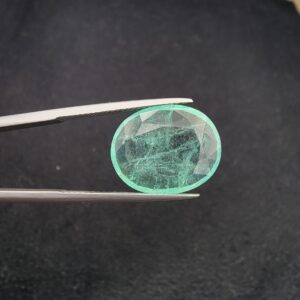 ​A rare 8.05-carat natural Pakistani Emerald gemstone resting flat on a white textured leather insert inside a display box. The loose, earth-mined beryl gem is precision cut into a well-proportioned oval shape, showcasing a vibrant, minty green body color and a highly transparent core filled with mesmerizing, beautiful natural internal inclusions.