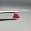 ​A 0.55 carat natural red Ruby (Yaqoot) from Kabul, Afghanistan, featuring a sharp triangle cut with rich color and natural internal silk, held in jeweler's tweezers.