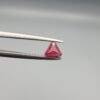 ​A 0.55 carat natural red Ruby (Yaqoot) from Kabul, Afghanistan, featuring a sharp triangle cut with rich color and natural internal silk, held in jeweler's tweezers.