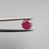 ​A 0.59 carat natural red Ruby (Yaqoot) from Kabul, Afghanistan, with a brilliant round cut, showcasing natural internal silk and vibrant saturation, held in jeweler's tweezers.