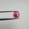 ​A 0.59 carat natural red Ruby (Yaqoot) from Kabul, Afghanistan, with a brilliant round cut, showcasing natural internal silk and vibrant saturation, held in jeweler's tweezers.