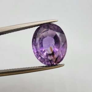 Natural Amethyst Katela gemstone 10.21 carats from Brazil with light purple color, oval faceted cut and visible natural inclusions held in tweezers