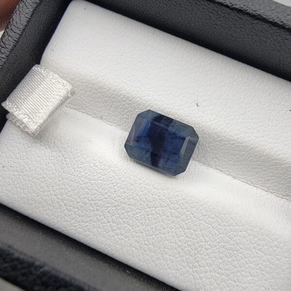 Natural Blue Sapphire Neelam 4.61 carat from Afghanistan with deep blue color, emerald step cut and visible natural inclusions displayed on white cushion