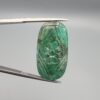Massive 32.08 carat natural green emerald gemstone, intricate hand-carved floral design from Zambia, held in professional jewelry tweezers.