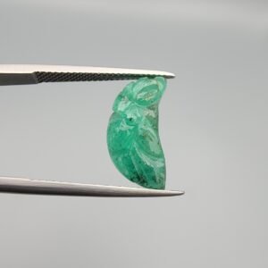 Exquisite hand-carved natural green emerald gemstone, 6.33 carats, featuring a detailed floral pattern from Zambia, held in professional jewelry tweezers.