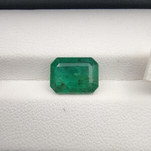 Octagon step cut natural green emerald gemstone, 3.41 carats, ethically sourced from Zambia, displayed in professional jewelry tweezers.