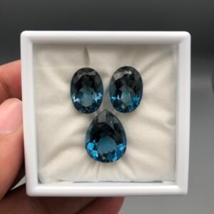 High-grade 28.33 carat total weight natural London Blue Topaz gemstone set, featuring a perfectly matched pair of pear-shaped stones and a central pear-shaped piece for a pendant.