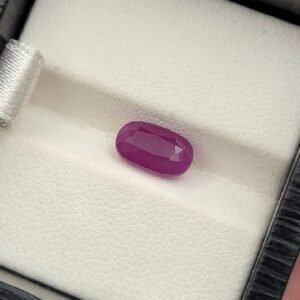 Natural 2.05 carat red ruby gemstone from Mozambique, featuring a vivid oval cut and high crystalline transparency, professionally displayed in jewelry tweezers.