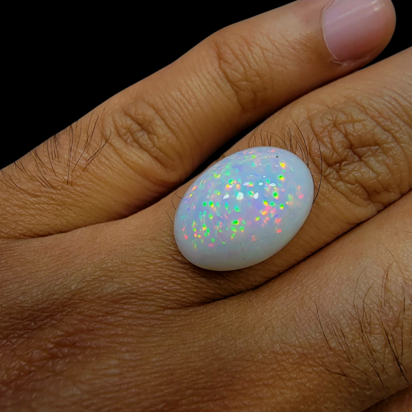Rare 9 carat natural white Ethiopian opal featuring a distinct star-like "pinfire" play-of-color and high-dome oval cabochon cut.
