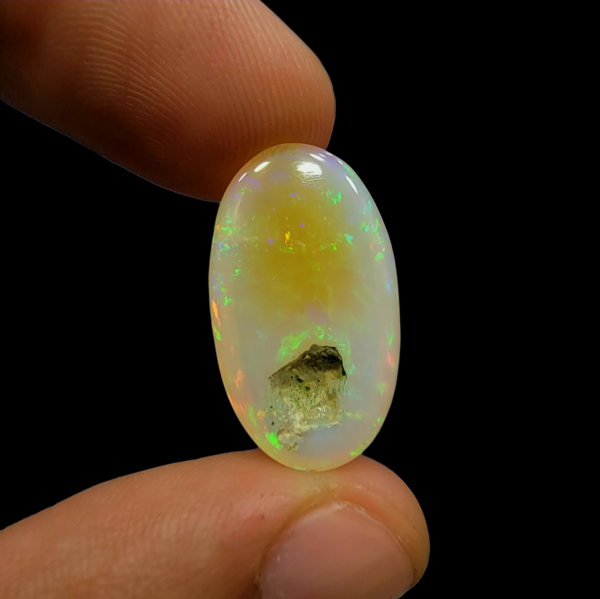 Magnificent 17.33 carat natural Ethiopian Welo opal featuring a vibrant "Neon Fire" play-of-color and a unique, naturally formed hole or hollow, showcasing its authentic volcanic origin.