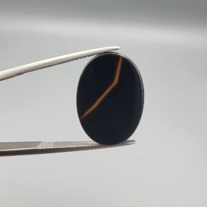 Polished 7.10 carat natural black chalcedony agate (Sulemani Aqeeq) gemstone featuring a smooth oval cabochon cut and a sharp, angular orange-gold banding line.