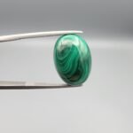 High-polished 17.81 carat natural malachite (Dana-e-Farhang) gemstone featuring swirling, multi-tonal green banding and orbital patterns in a smooth oval cabochon cut.
