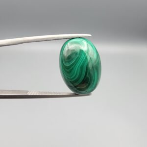 High-polished 17.81 carat natural malachite (Dana-e-Farhang) gemstone featuring swirling, multi-tonal green banding and orbital patterns in a smooth oval cabochon cut.