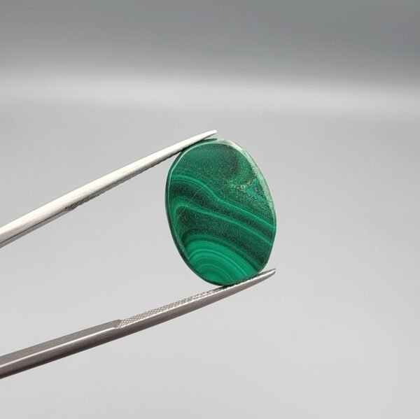 High-polished 17.81 carat natural malachite (Dana-e-Farhang) gemstone featuring swirling, multi-tonal green banding and orbital patterns in a smooth oval cabochon cut.