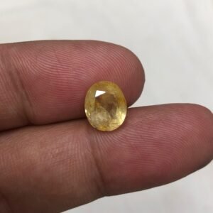 Certified 4.42 carat natural yellow sapphire (Pukhraj) from Sri Lanka, featuring an oval shape and a bright, unheated lemon-yellow color, shown held between fingers to showcase scale.