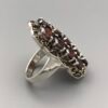 Vintage-style sterling silver statement ring featuring 13 natural oval-cut garnets in a vertical cluster setting, totaling 15 carats.