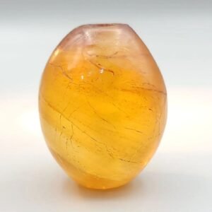 Translucent 226-carat natural copal "Young Amber" gemstone with a polished egg-like shape, displaying a warm golden-orange clarity and internal organic characteristics.