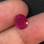 GGI certified 2.43 carat natural Mozambique ruby with a purplish red color, oval mixed cut, and transparent clarity, shown alongside its official gemstone report.