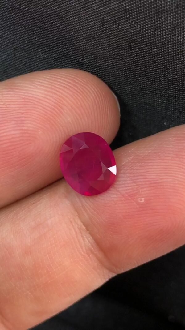 GGI certified 2.43 carat natural Mozambique ruby with a purplish red color, oval mixed cut, and transparent clarity, shown alongside its official gemstone report.