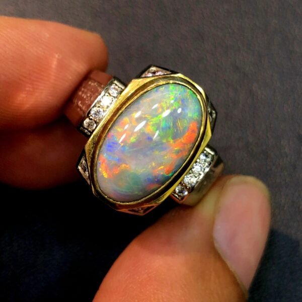 A custom-made sterling silver ring featuring a 4.40ct natural Australian opal cabochon with vibrant orange, green, and blue fire, accented by small round diamonds on a sturdy split-shank band.