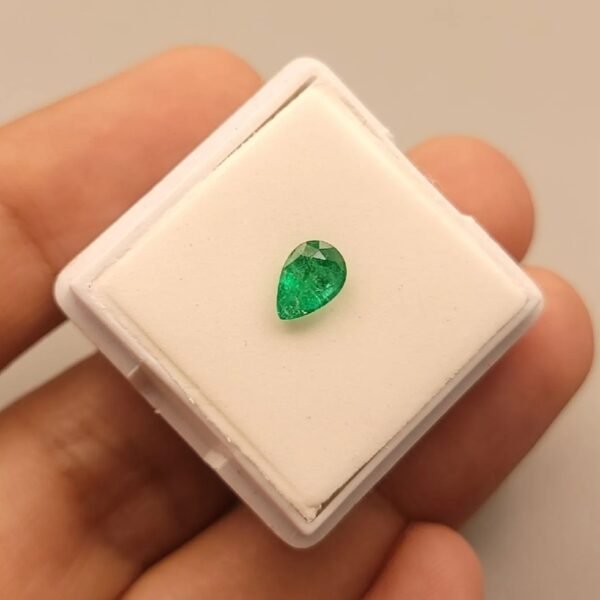 Vibrant 0.70 carat natural Swat emerald with a classic pear-shaped brilliant cut, showcasing the signature deep "Swat green" color and characteristic inclusions, presented in a gemstone box.