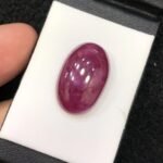 GGI certified 22.41 carat natural star ruby featuring a translucent red body and a smooth oval cabochon cut.