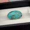 Vibrant 9.73 carat natural Egyptian turquoise (Feroza) oval cabochon featuring a bright sky-blue base with a fine, dark web-like matrix, presented in a black jeweler's display box.