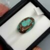 Vibrant 9.73 carat natural Egyptian turquoise (Feroza) oval cabochon featuring a bright sky-blue base with a fine, dark web-like matrix, presented in a black jeweler's display box.