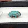 Premium 10.40 carat natural Egyptian turquoise (Feroza) oval cabochon displaying a vivid sky-blue body with an intricate, dark chocolate-brown spiderweb matrix, shown in a black jeweler's box.