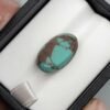 Premium 10.40 carat natural Egyptian turquoise (Feroza) oval cabochon displaying a vivid sky-blue body with an intricate, dark chocolate-brown spiderweb matrix, shown in a black jeweler's box.