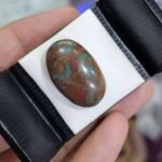 Oversized 24.63 carat natural Egyptian turquoise (Feroza) oval cabochon with a vivid teal-blue body and a dense, earthy reddish-brown iron stone matrix.