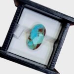 ​A 2.56 carat natural Egyptian turquoise (Feroza) oval cabochon with a bright mint-to-sky blue body and rich reddish-brown iron stone matrix along the edges.