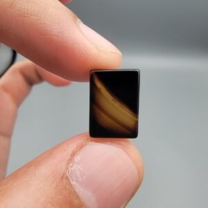 A 5.20 carat natural Black Agate (Sulemani Aqeeq) with a unique white foam pattern resembling wings, held in tweezers against a dark background.