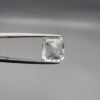 ​A 3.77 carat natural emerald-cut Aquamarine (Beruj) from Shigar Valley, Pakistan, displaying distinct black needle-like and "mountain" inclusions on the reverse side, held in jeweler's tweezers.
