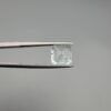 A 2.60 carat natural emerald-cut Aquamarine (Beruj) from Shigar Valley, Pakistan, held in tweezers, showing a clear face and a back side with distinct black needle-like mountain inclusions.