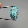 An exceptionally large 45.93-carat natural Iranian Turquoise (Feroza) from Kerman City, featuring a high-domed oval cabochon cut with a vivid blue base and dense metallic pyrite inclusions.