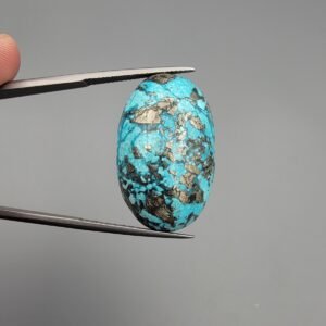 An exceptionally large 45.93-carat natural Iranian Turquoise (Feroza) from Kerman City, featuring a high-domed oval cabochon cut with a vivid blue base and dense metallic pyrite inclusions.