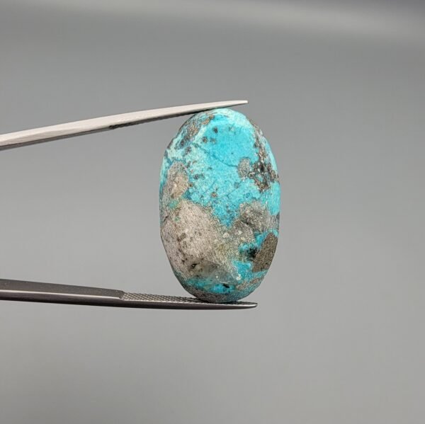 An exceptionally large 45.93-carat natural Iranian Turquoise (Feroza) from Kerman City, featuring a high-domed oval cabochon cut with a vivid blue base and dense metallic pyrite inclusions.