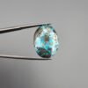 ​A 24.62-carat natural Iranian Turquoise (Feroza) from Kerman City, featuring a large oval cabochon cut with a vivid blue base and a beautiful web of metallic pyrite inclusions.