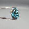 ​A 24.62-carat natural Iranian Turquoise (Feroza) from Kerman City, featuring a large oval cabochon cut with a vivid blue base and a beautiful web of metallic pyrite inclusions.