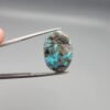 ​A 24.62-carat natural Iranian Turquoise (Feroza) from Kerman City, featuring a large oval cabochon cut with a vivid blue base and a beautiful web of metallic pyrite inclusions.