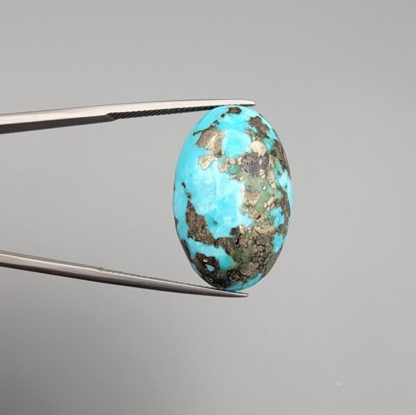 A massive 35.11-carat natural Iranian Turquoise (Feroza) from Kerman City, featuring a high-domed oval cabochon cut, saturated sky-blue color, and a brilliant golden pyrite matrix, shown from multiple angles.