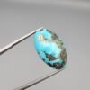 A massive 35.11-carat natural Iranian Turquoise (Feroza) from Kerman City, featuring a high-domed oval cabochon cut, saturated sky-blue color, and a brilliant golden pyrite matrix, shown from multiple angles.