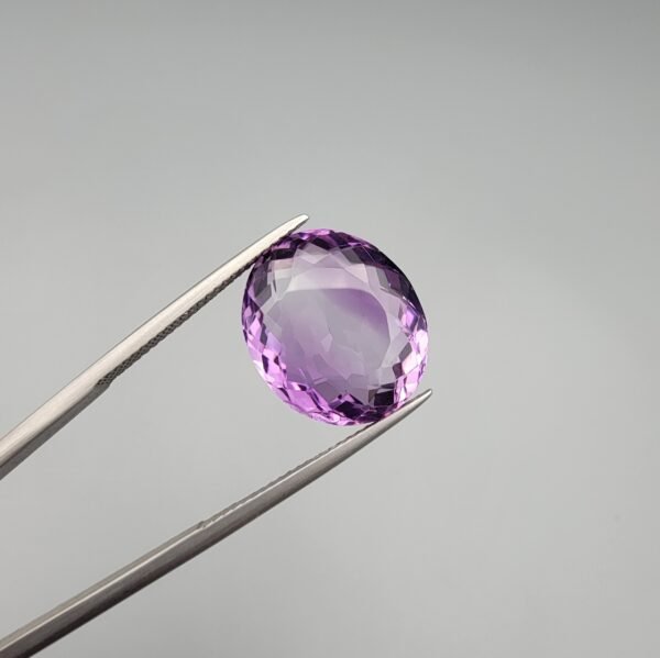 A 11.05-carat natural purple Amethyst (Katela) from Brazil, featuring a brilliant oval faceted cut with exceptional clarity and deep violet saturation, shown in jeweler's tweezers.