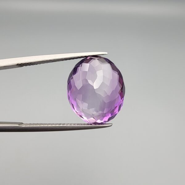 A 11.05-carat natural purple Amethyst (Katela) from Brazil, featuring a brilliant oval faceted cut with exceptional clarity and deep violet saturation, shown in jeweler's tweezers.