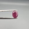 ​A 4.61-carat natural Mozambique Ruby (Yaqoot) gemstone, featuring a brilliant oval faceted cut with a rich pigeon-blood red hue and excellent transparency, held in jeweler's tweezers.