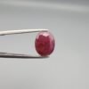 ​A 3.81-carat natural Mozambique Ruby (Yaqoot) gemstone in a brilliant oval faceted cut, displaying a rich red color with natural black silk inclusions that remain eye-clean, held in jeweler's tweezers.