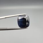 A 10.95-carat natural deep blue Sapphire from Afghanistan, featuring a professional oval facet cut, presented in a jeweler's display case.