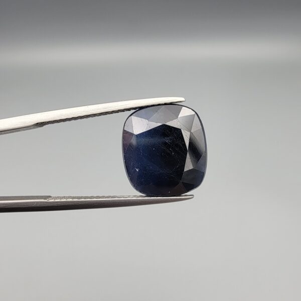 A 10.95-carat natural deep blue Sapphire from Afghanistan, featuring a professional oval facet cut, presented in a jeweler's display case.